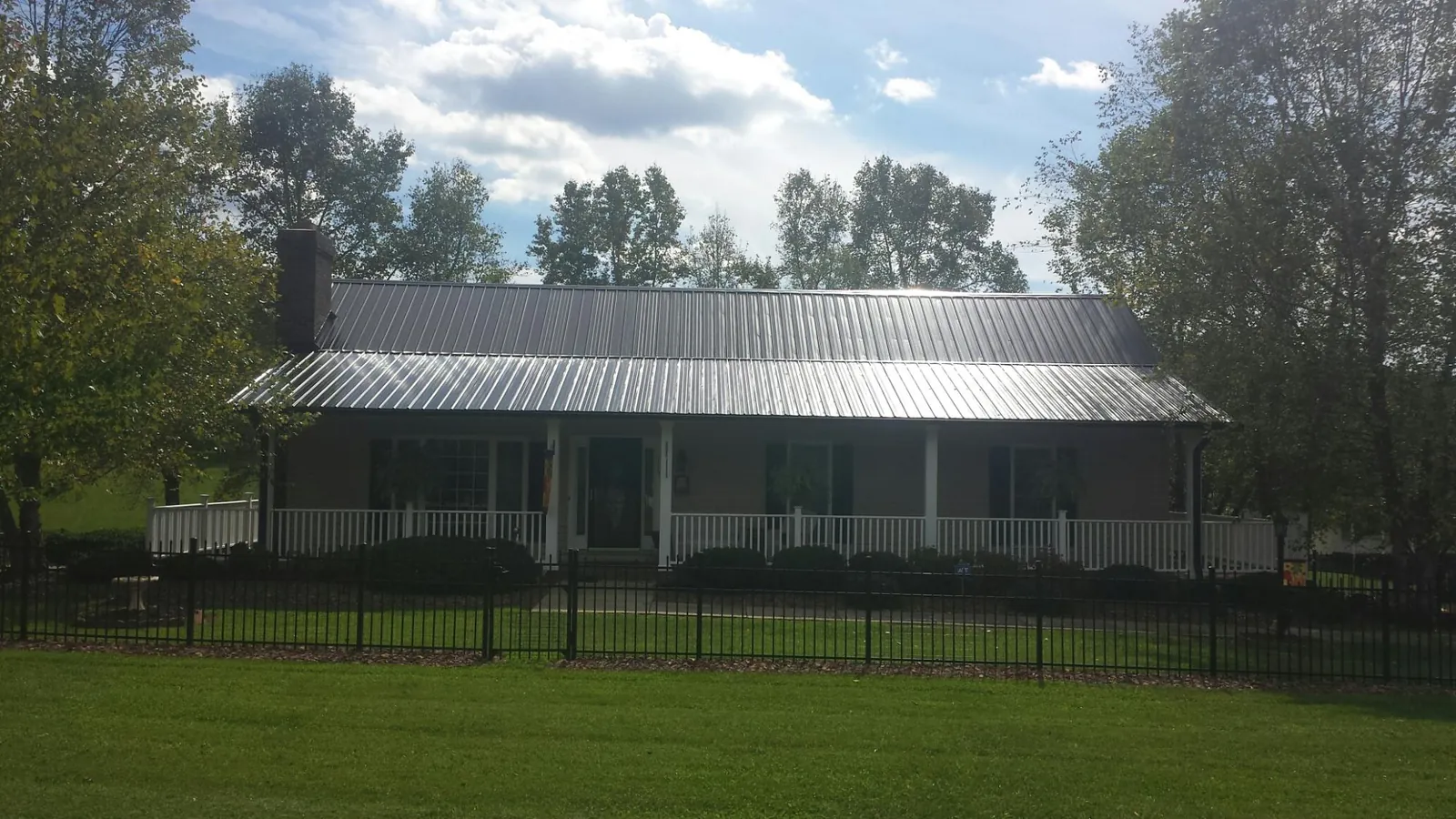 Gray metal roof on a brick ranch with a full width front porch — Gutter Guard Installation work by our crew in Saint Louis